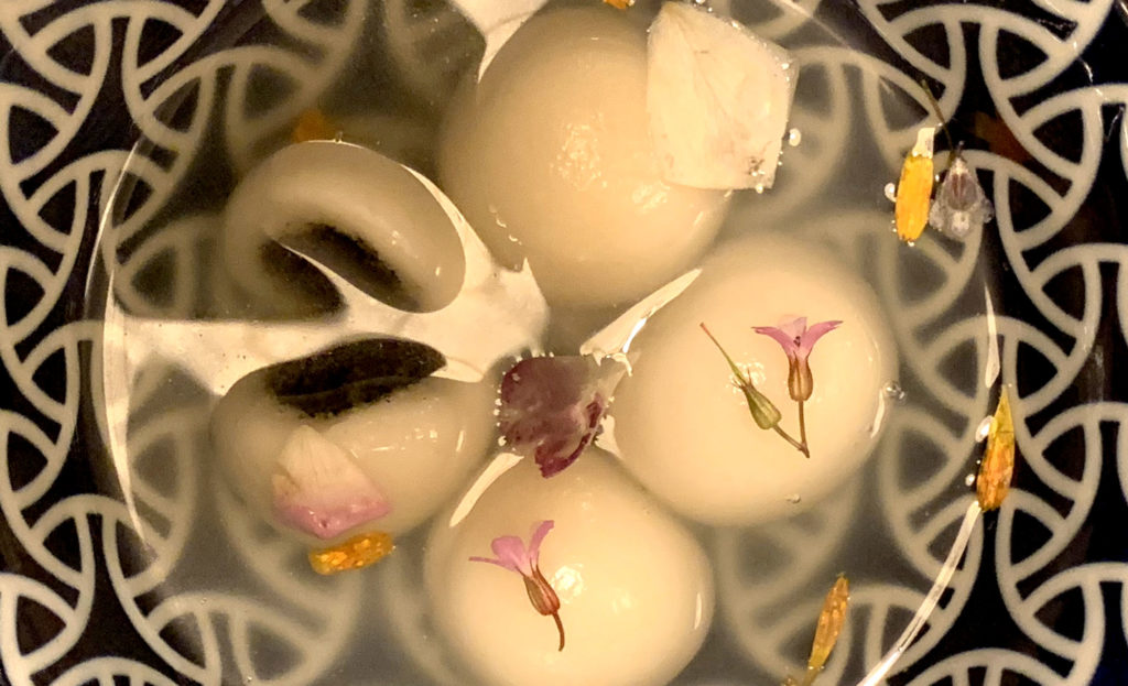 Les tang yuan sont servies avec du bouillon de cuisson et des fleurs comestibles